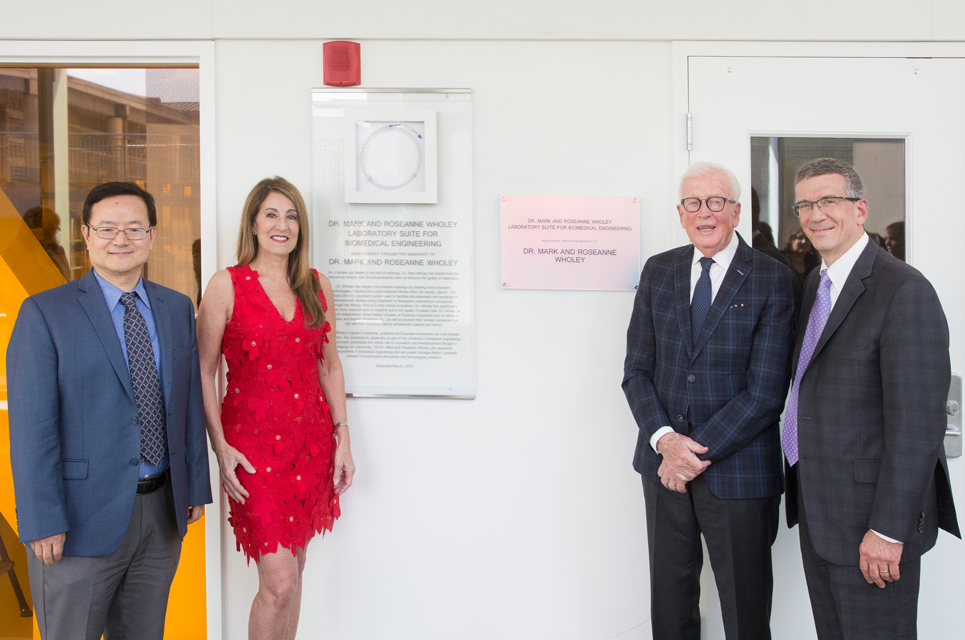 The Wholeys posing on either side of the entrance to the new lab, with the provost and BME department head.