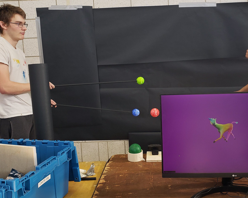Student moving small spheres in front of a black background