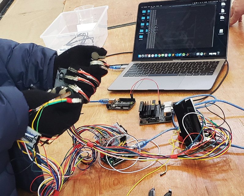 Gloves with multi-colored wires connected to a laptop