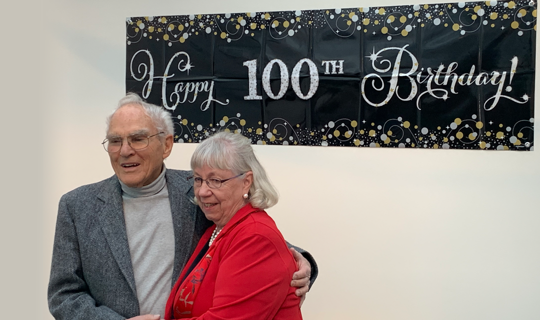 Meyer and a woman in from of a "Happy 100th birthday!" banner